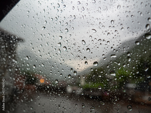Gotas de agua de lluvia sobre un cristal con el paisaje borroso al fondo, en la noche de verano de 2021.