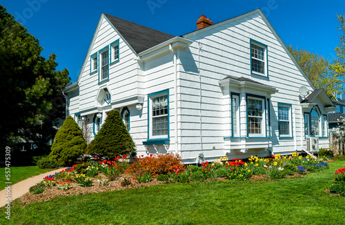 An older style tradional home with flower beds full of springtime flowers.