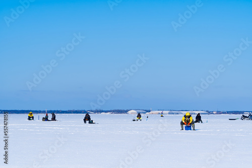 Ice Fishing. Winter fishing on ice at sea, Estonia. Anglers with equipment fishing on the lake ice