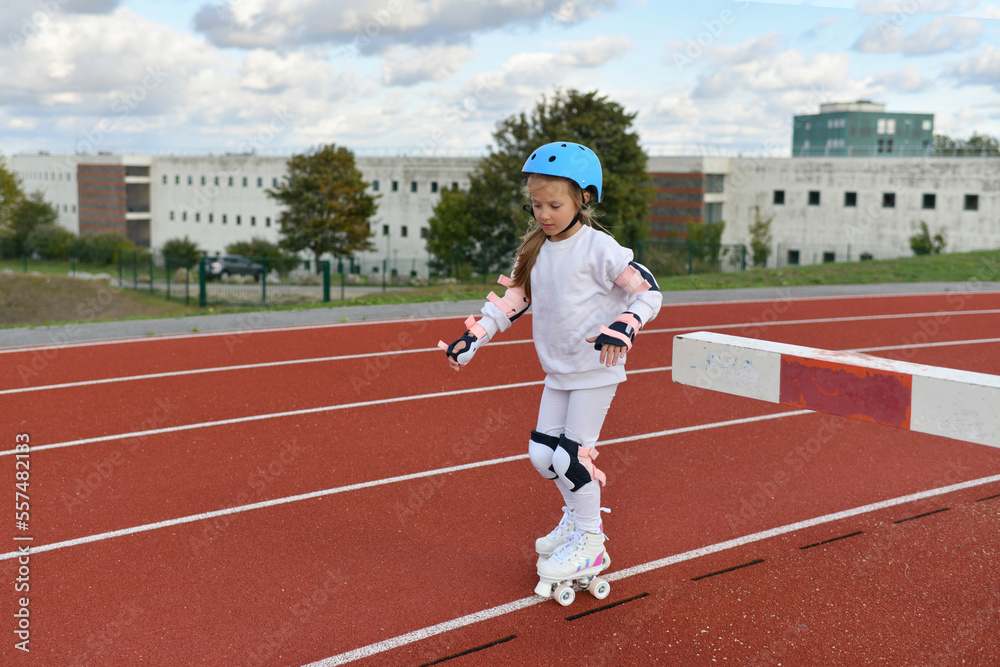 Obraz premium A girl in vintage white roller skates and a helmet at the stadium