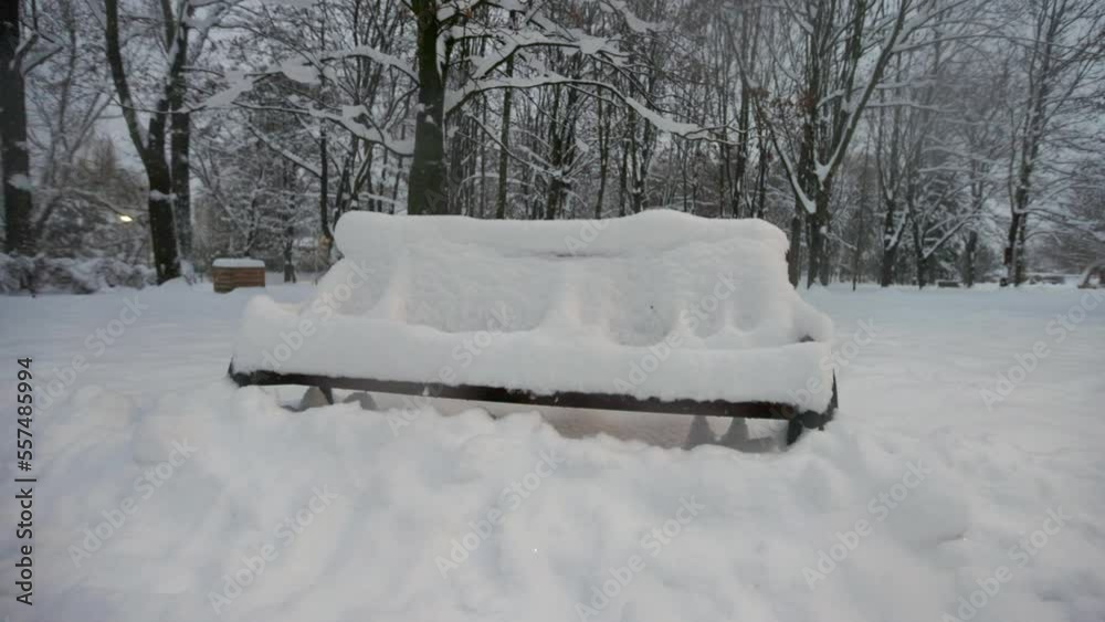 Snow-covered bench in the winter public park at twilight.