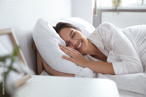 Fotobehang Happy young woman lying on soft pillow in bed at home