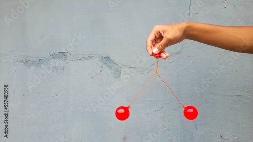 Kid holding lato-Lato. A traditional toy consisting of two heavy pendulums made of plastic and suspended by a string. Its  traditional game can be found in Indonesia. These lato-lato have been very ic