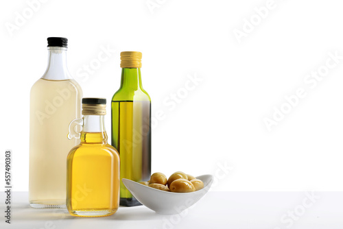 Bottles of different cooking oils and olives on white background, space for text