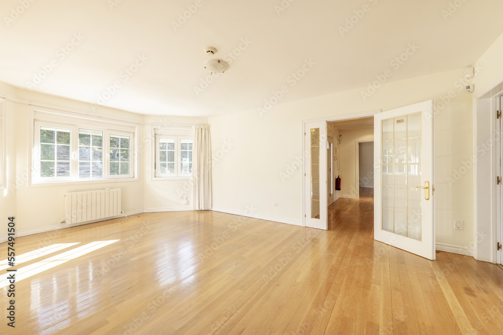 Empty living room with French oak hardwood floors, white lacquered wood door joinery with gold-edged French windows and French-style windows - obrazy, fototapety, plakaty 