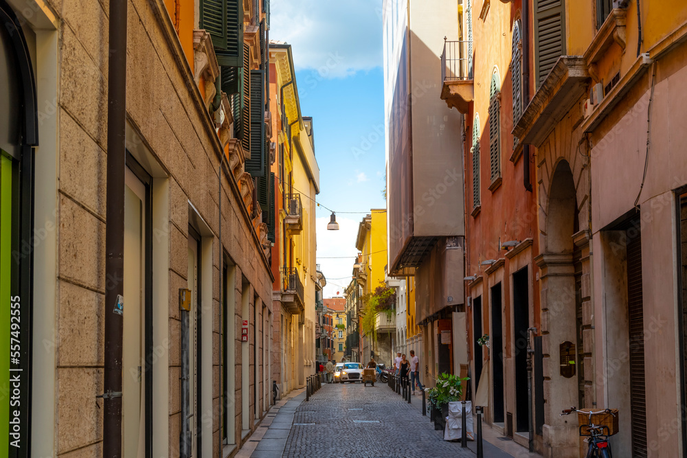 A narrow street of shops and cafes in the historic medieval old town center of Verona, Italy.	