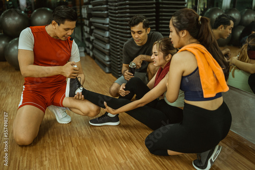 asian male instructor straightens leg of woman having muscle cramps during exercise in fitness center