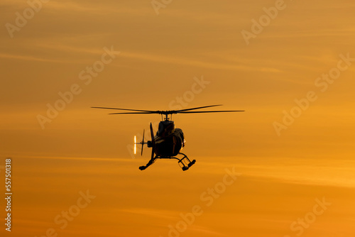 Tourist helicopter flying in the sky at sunset.