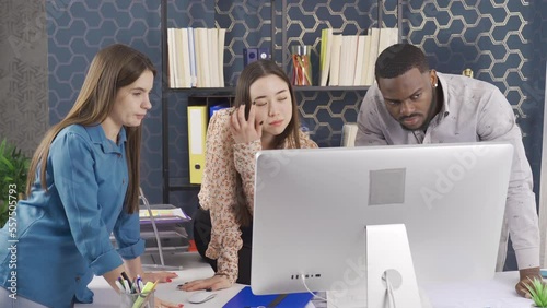 Wallpaper Mural Office workers of different races work together in the office.
African man, Asian and European woman working together in office. They are looking at the computer screen and talking.
 Torontodigital.ca