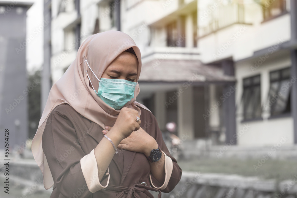 Woman in hijab coughs and wears medical mask because of air pollution Woman in hijab coughs and wears medical mask because of air pollution
