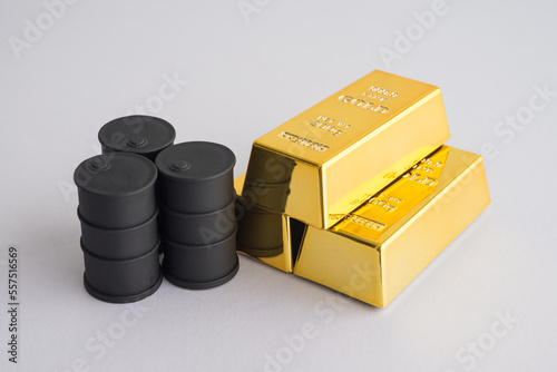 Black crude oil tanks vs gold bars on white background copy space. Commodity trading, investment, risk management, invest trategy plan, relationship between gold and oil price concept. photo