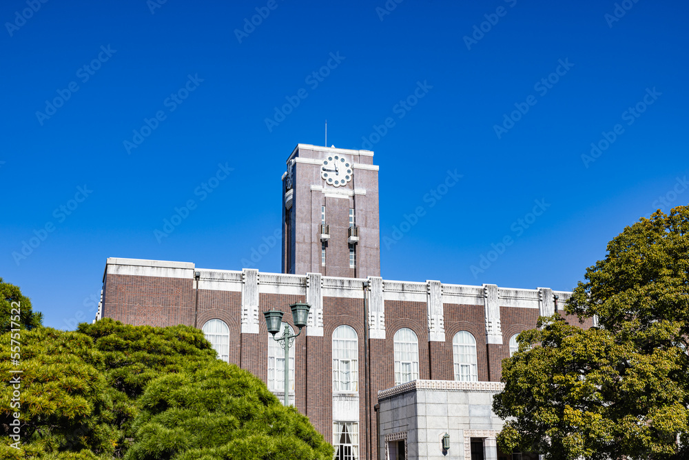 Naklejka premium Kyoto University Clock Tower Centennial Hall and the Camphor Tree under the clear sky. This tower had been loved as the university's symbol.