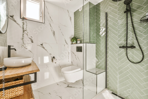 a modern bathroom with green tiles and white marble flooring on the walls, along with a wooden vanity sink
