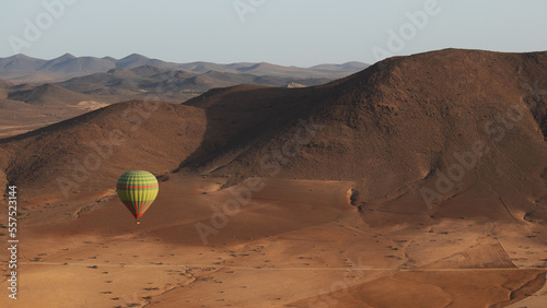 hot air balloon flying over the stone desert in Marrakesh with mountains in the background