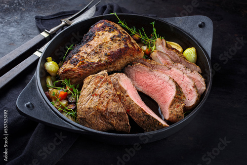 Tafelspitz Braten vom Kalb mit Gemüse, Pilzen und Kräuter serviert mit Dunkelbier Sauce als close-up in einem gusseisernen Guss Topf 