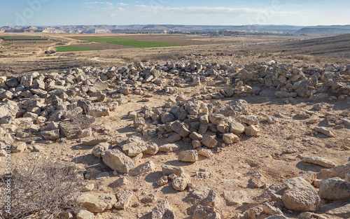 ancient atone ruins high on a hill above Kibbutz Sde Boker with the cliffs of the Nahal Zin stream and a blue sky background