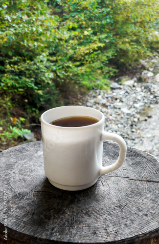 Cup of coffee on mountain river background.