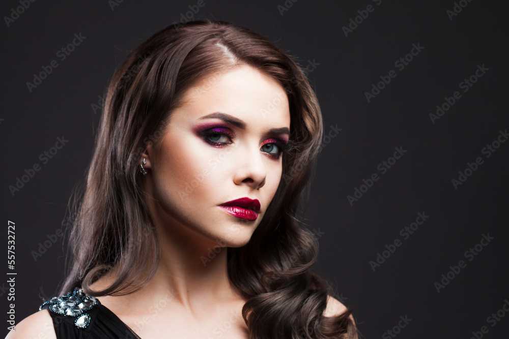 Fototapeta premium Gorgeous young brunette in a chic evening look. Scarlet lips and eye shadow, wave hair styling