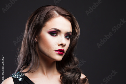 Gorgeous young brunette in a chic evening look. Scarlet lips and eye shadow, wave hair styling