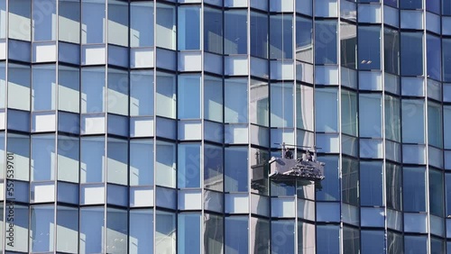 オフィスビルのガラス窓をゴンドラに乗って清掃をする作業員 photo