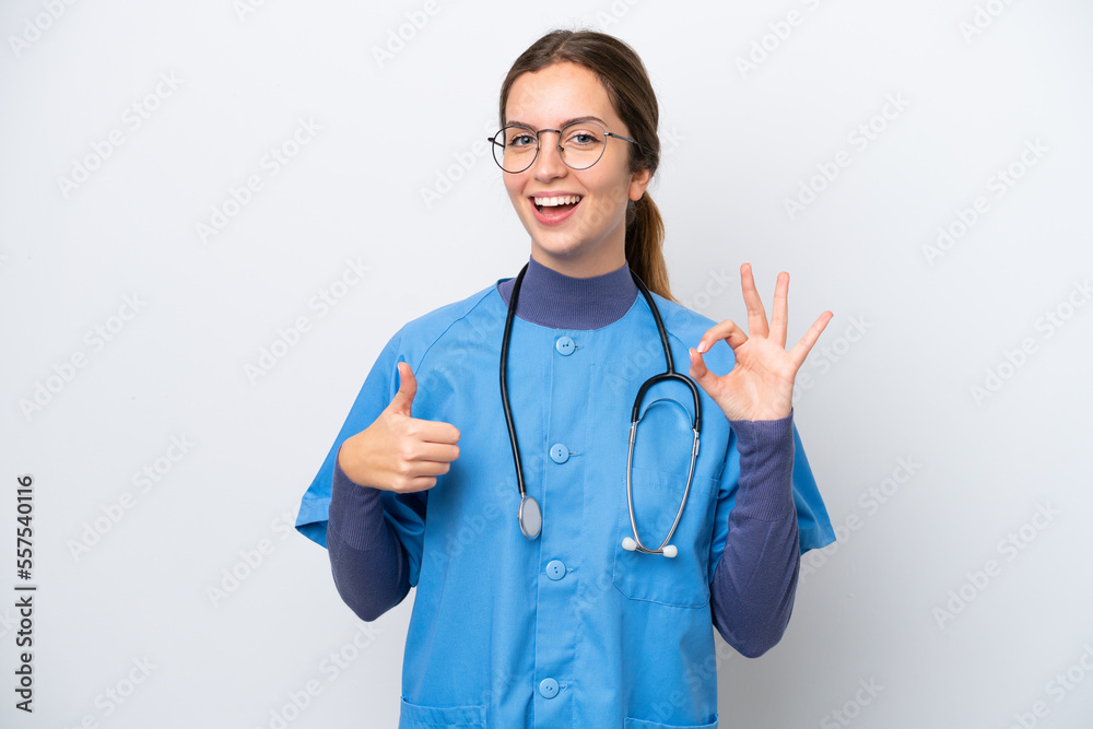 Young caucasian nurse woman isolated on white background showing ok sign and thumb up gesture Young caucasian nurse woman isolated on white background showing ok sign and thumb up gesture