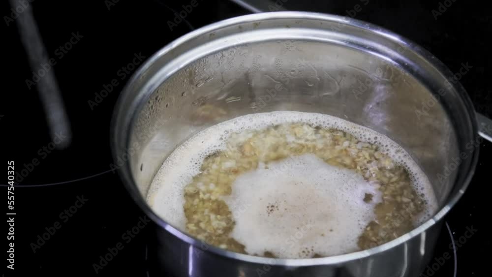 Buckwheat porridge is cooked in metal saucepan. Kitchen cooking food on induction cooker