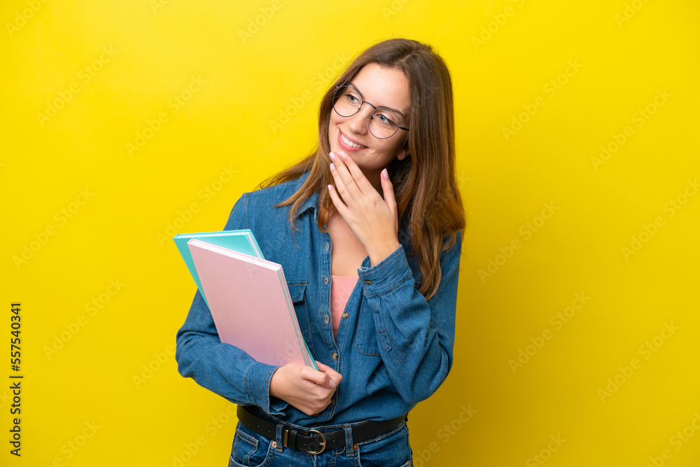 Young student caucasian woman isolated on yellow background looking up while smiling Young student caucasian woman isolated on yellow background looking up while smiling