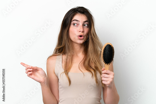 Young woman with hair comb isolated on white background surprised and pointing side