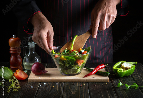 Professional chef cooks a delicious vegetable salad. Vegetarian food by hands of the cook in the kitchen. Menu idea for a hotel or restaurant