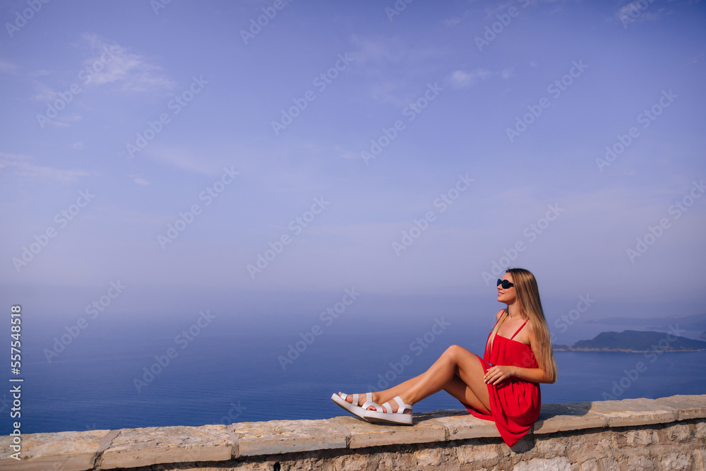 Tourist woman in red dress enjoying view on Adriatic sea on sunny day Tourist woman in red dress enjoying view on Adriatic sea on sunny day