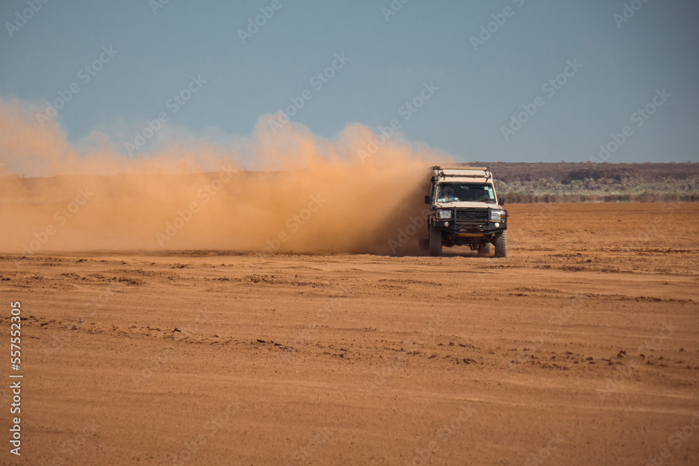 A tourist jeep on a dirt road amidst acacia trees in Chalbi Desert, Marsabit County, Kenya