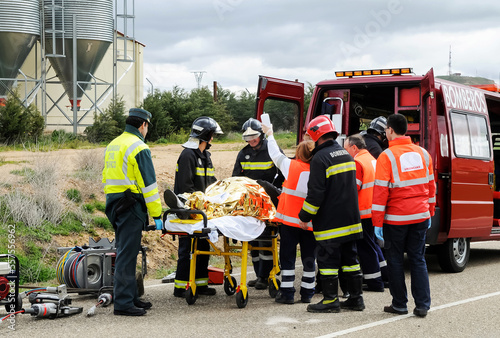 Victim of a traffic accident is attended by public emergency services with firefighters, paramedics and police.