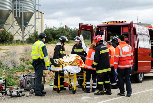 Billede på lærred Victim of a traffic accident is attended by public emergency services with firefighters, paramedics and police