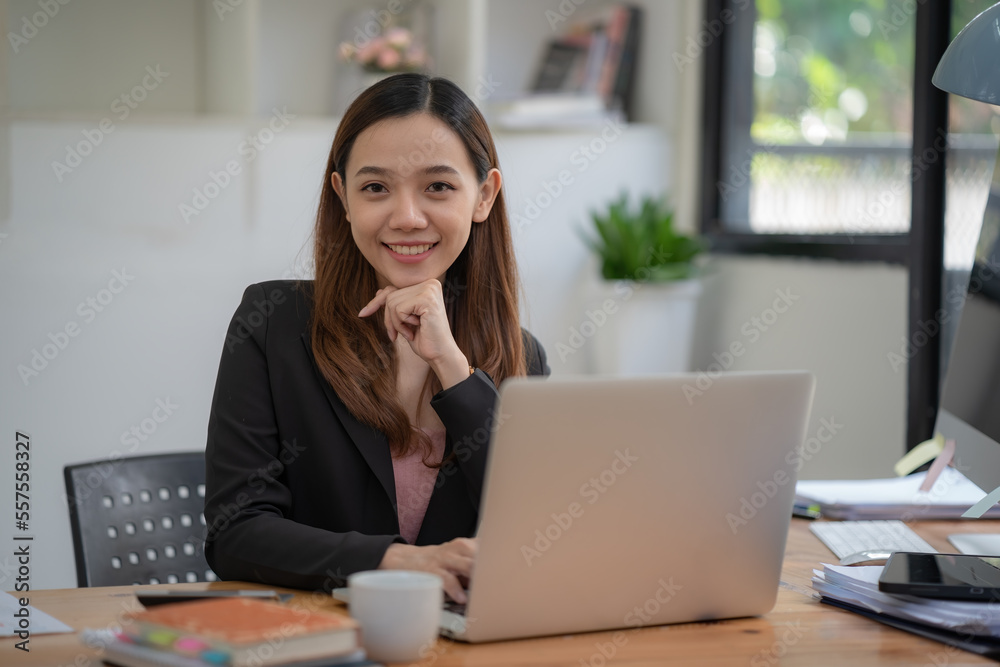 A pretty businesswoman smiles at the camera while sitting at her desk in front of the computer. A pretty businesswoman smiles at the camera while sitting at her desk in front of the computer.