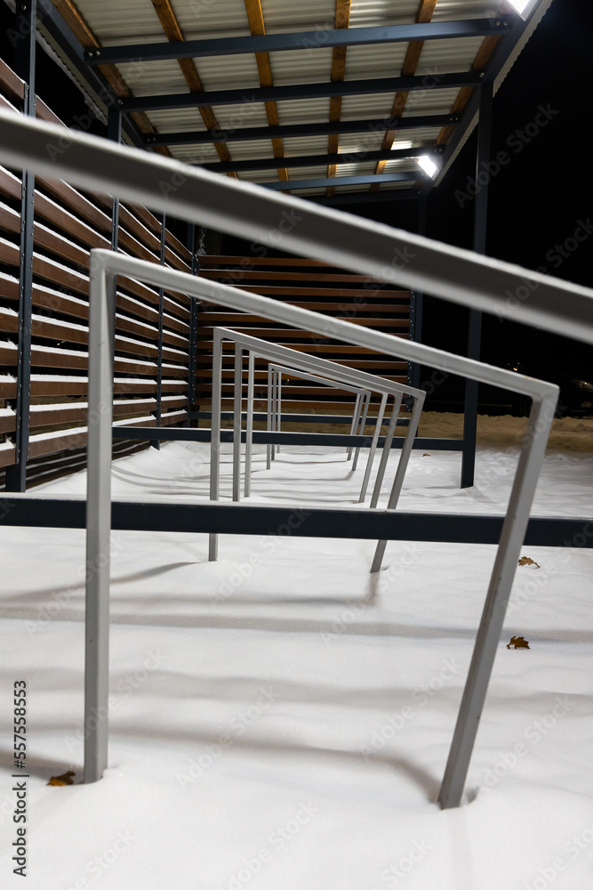 Obraz premium Empty shed with bicycle racks in a city park in winter. Difficulties in traveling by bike in winter.