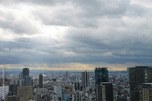 Overhead view of Osaka s Umeda area from a hill on a cloudy day  sunlight shining through a gap in the clouds.