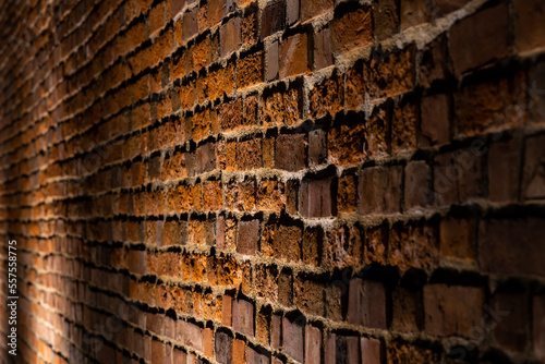 Obraz na płótnie A red brick wall illuminated at night. Surface texture emphasized by the angle of incidence of light w salonie