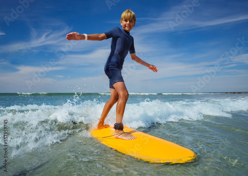 Boy learn to stand on the surf board standing at sea beach