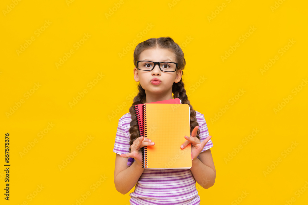A teenage girl in a striped purple T-shirt holds two notebooks and is surprised. A teenage girl in a striped purple T-shirt holds two notebooks and is surprised.