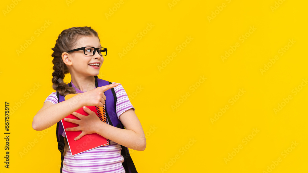 A schoolgirl with a briefcase and books on a yellow background points aside at your ad. A schoolgirl with a briefcase and books on a yellow background points aside at your ad.