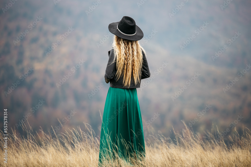 Φωτογραφία Young blonde girl walking on the field, in a hat and green dress in the outdoors