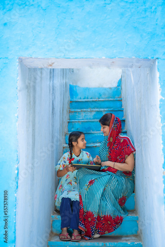 Indian rural woman teaching to her little daughter at home. © Niks Ads
