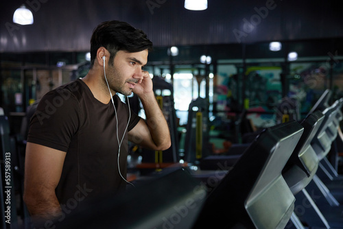young handsome man working out and running on treadmill in the gym
