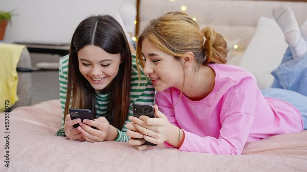 Adolescent girls having fun together using smartphone, sharing happy moments visiting each other Adolescent girls having fun together using smartphone, sharing happy moments visiting each other
