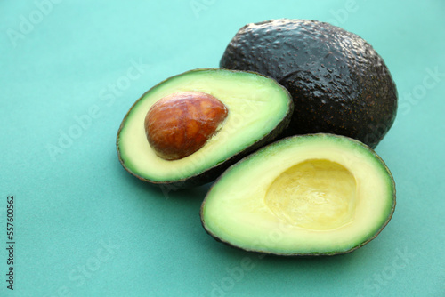 Tasty whole and cut avocados on turquoise background