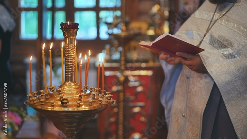 Принти на полотні Burning candles against the background of the Priest reading the Bible at the service