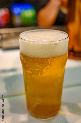 Fresh draught lager or IPA beer is glass served in indoor cafe close up, pint of beer