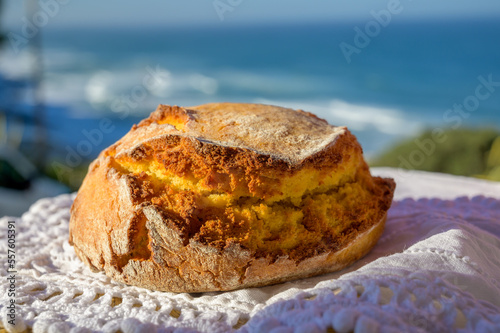 Portugeese homemade oven baked yellow corn bread served outdoor with view on blue Atlantic ocean in Lisbon area, Portugal photo