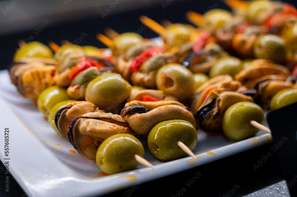 Fototapeta premium Typical snack of Basque Country, pinchos or pinxtos skewers with small pieces of bread, sea food, eggs, cheese, jamon served in bar in San-Sebastian or Bilbao, Spain