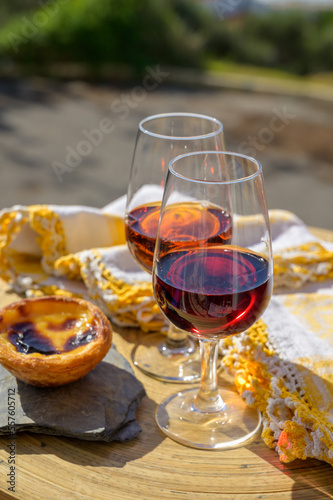 Portugal's food and drink, glass of porto wine, muscatel de setubal and sweet dessert Pastel de nata egg custard tart pastry served with view on blue Atlantic ocean in Lisbon area, Portugal photo